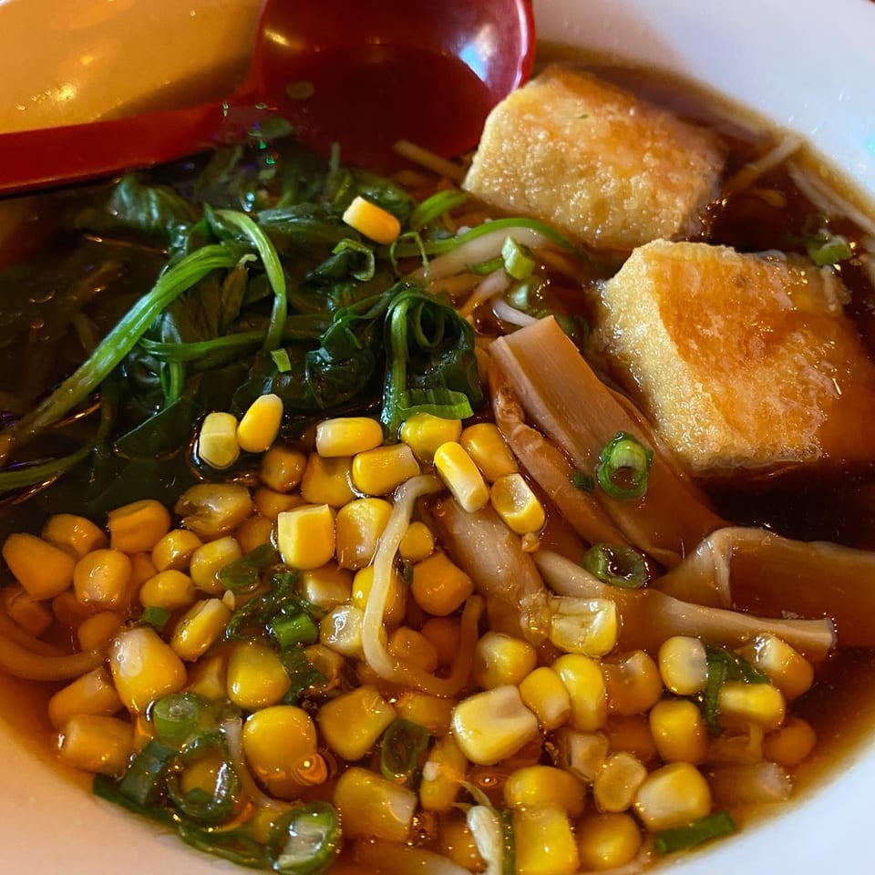 Close-up of Momo Ramen's ramen bowl with corn, greens, tofu, and bamboo shoots.